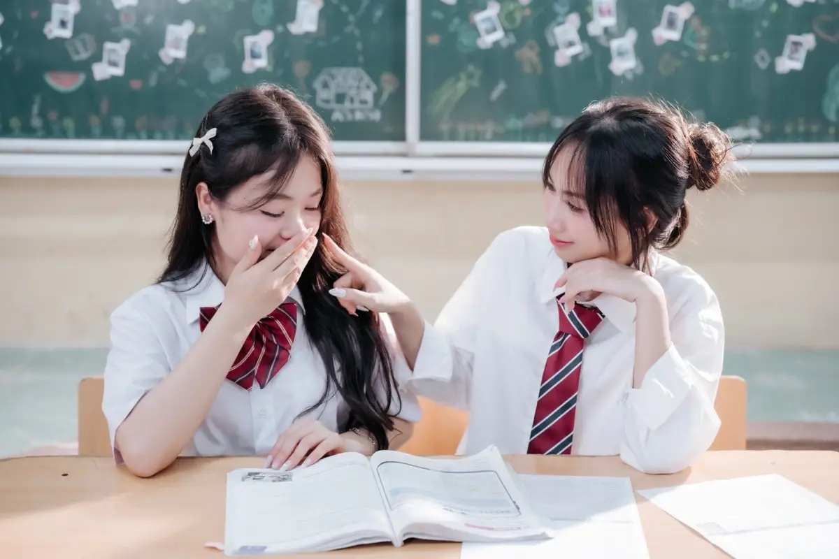 Two students studying together from an open book at a desk