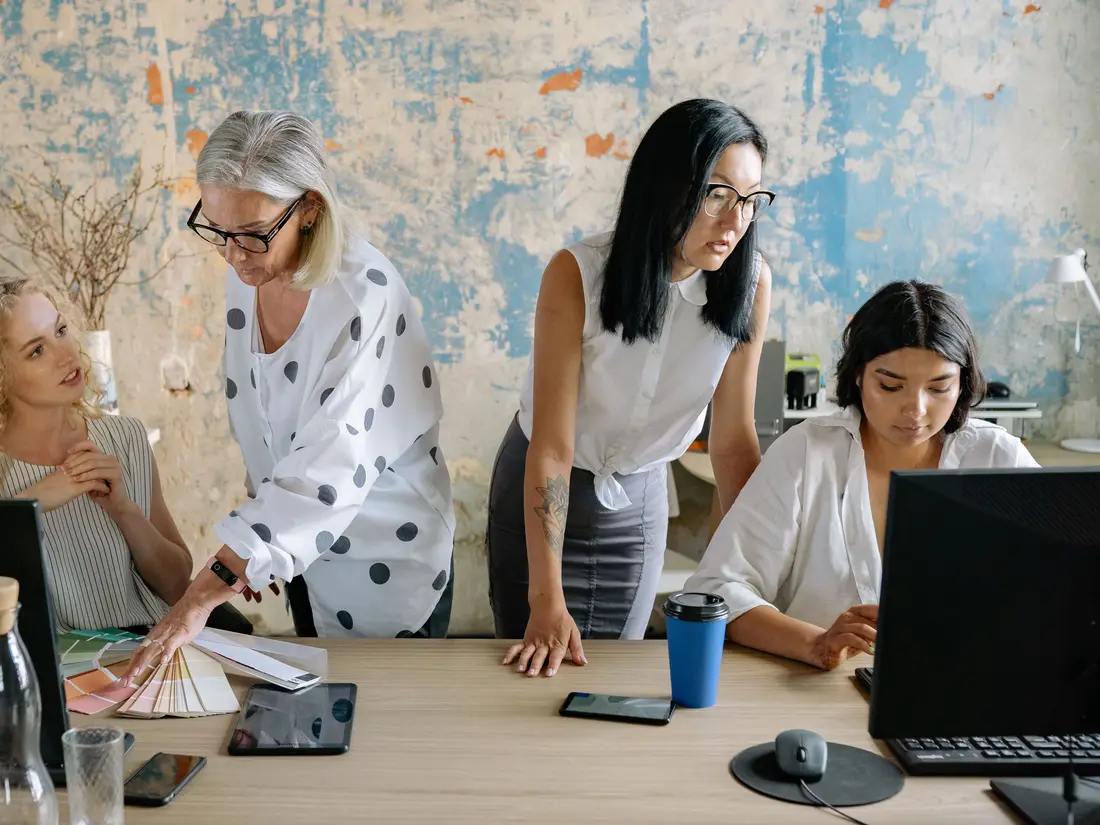Two colleagues reviewing paperwork together at a desk in a bright office